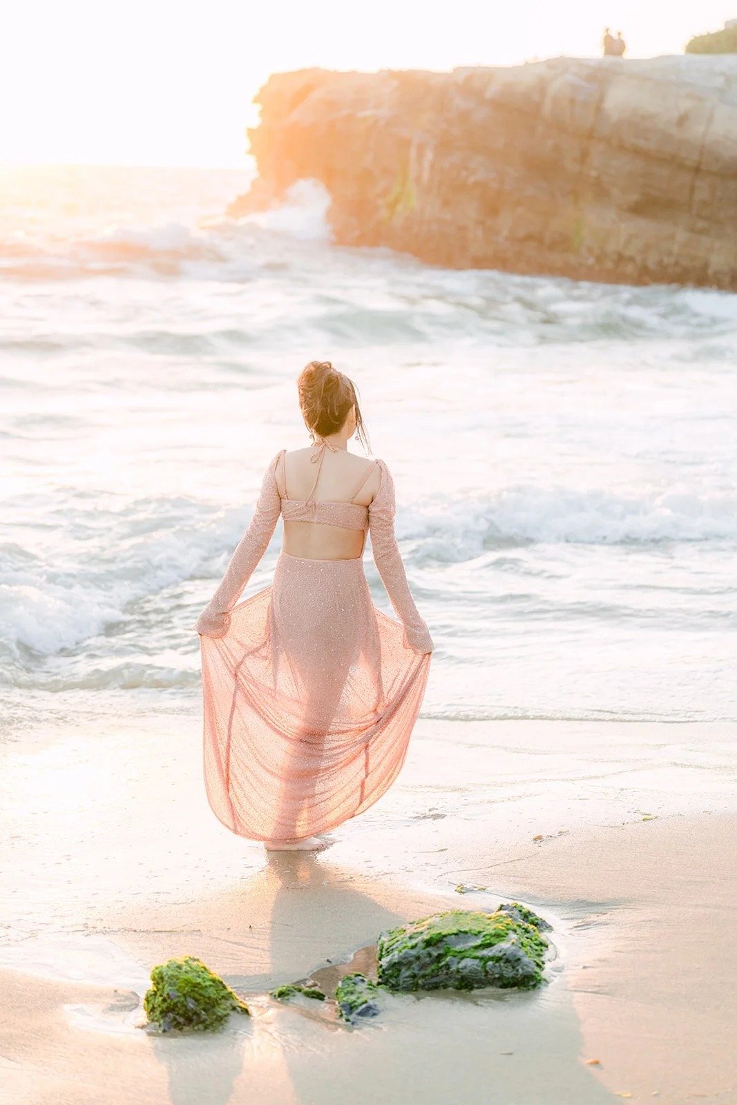 Amy walking into the waves with her pink gown in hand.