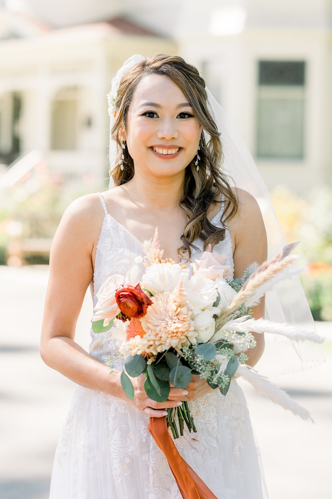 Ariel holding her peach and white bouquet with a long orange ribbon