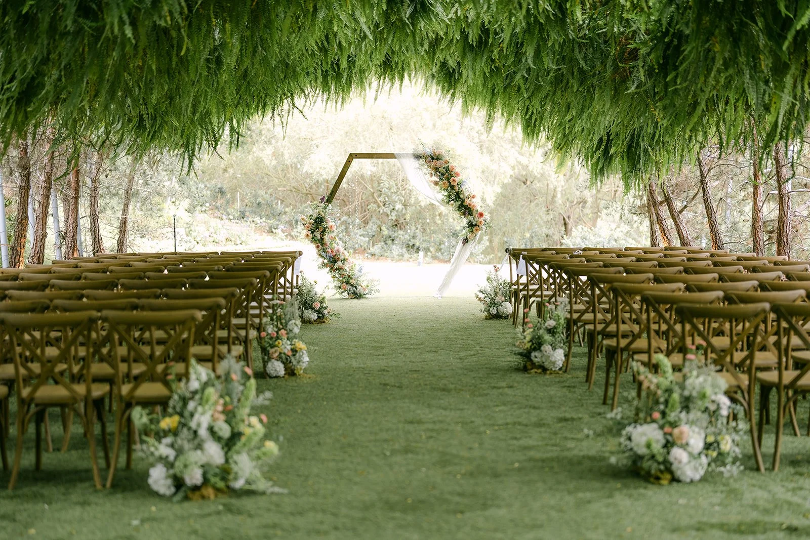Woodland Grotto ceremony aisle beneath hanging ferns at Ethereal Gardens