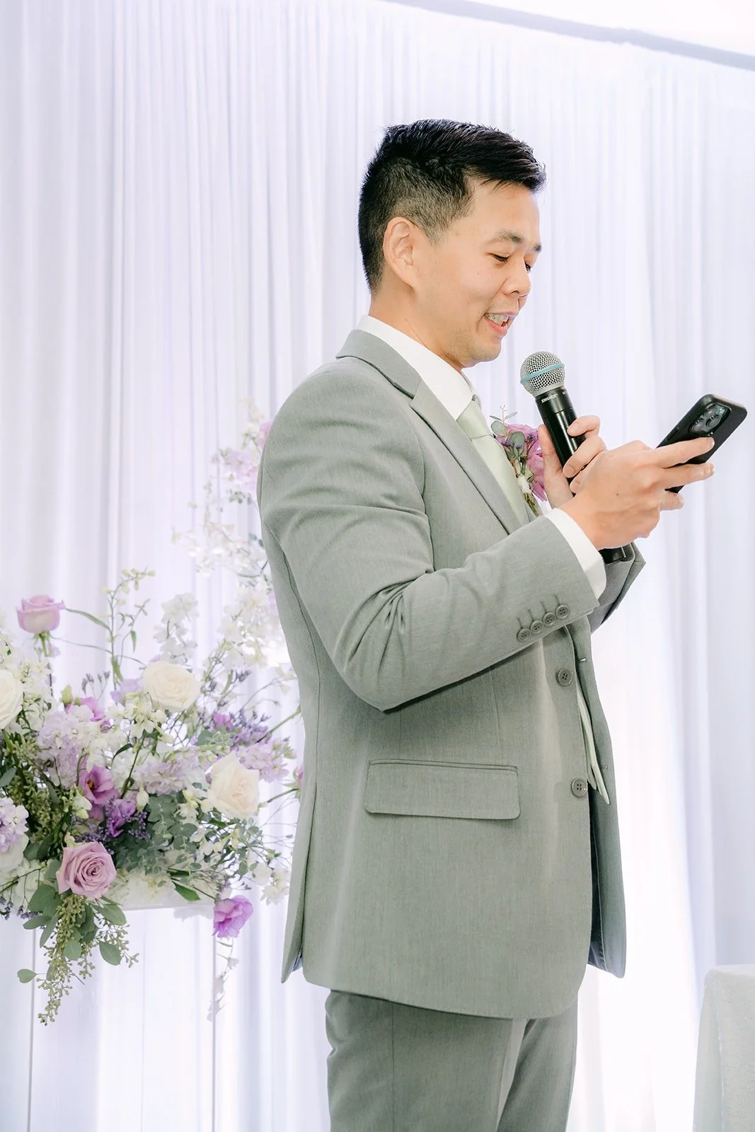 A groomsman reads his speech from his phone
