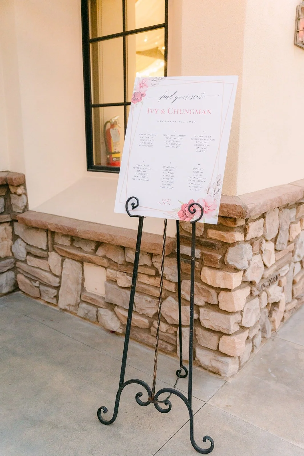 Seating chart on an easel by the stone wall