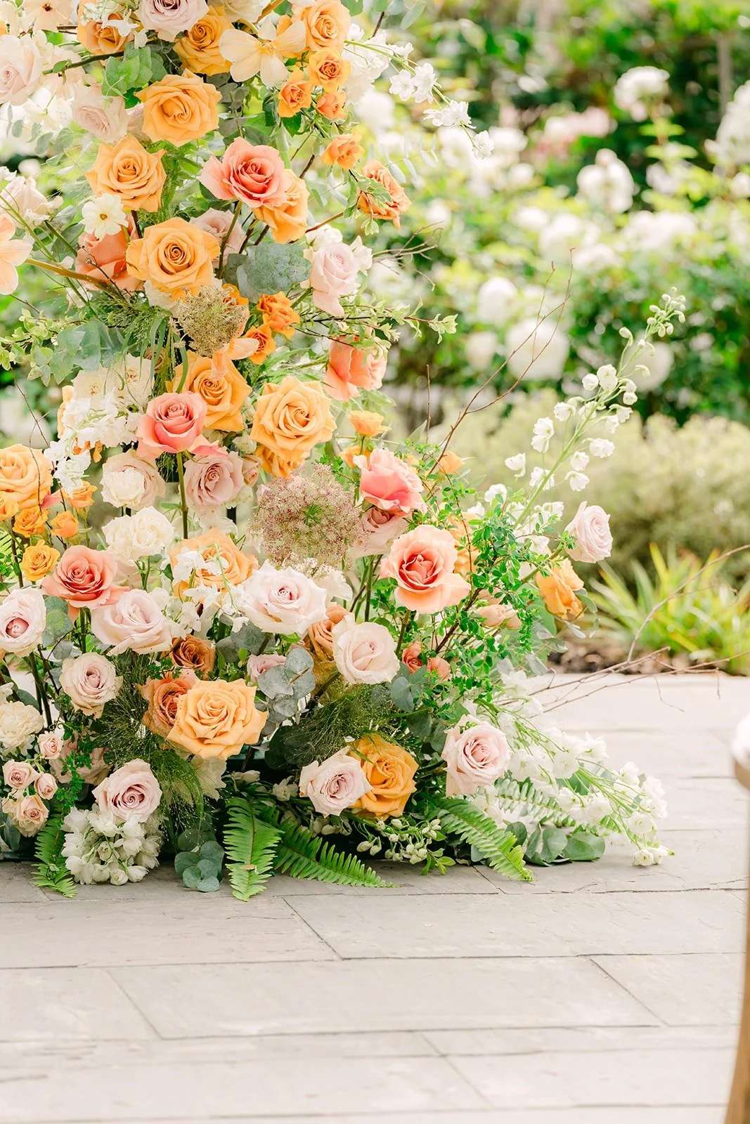 Peach and blush roses at the base of the ceremony arch