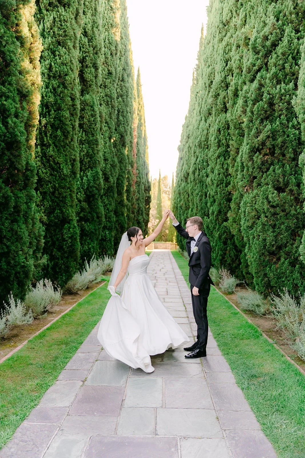Nik dipping Brianna between the tall cypress hedges