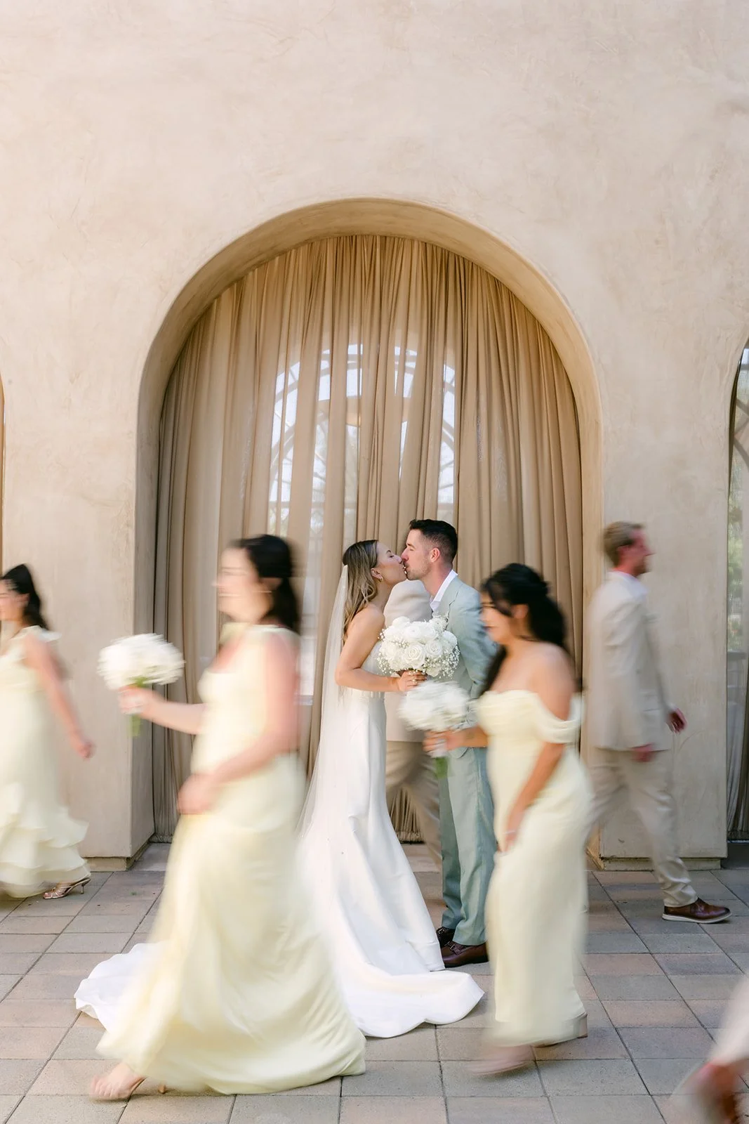 Bridesmaids in yellow walking past the couple in a candid motion photo