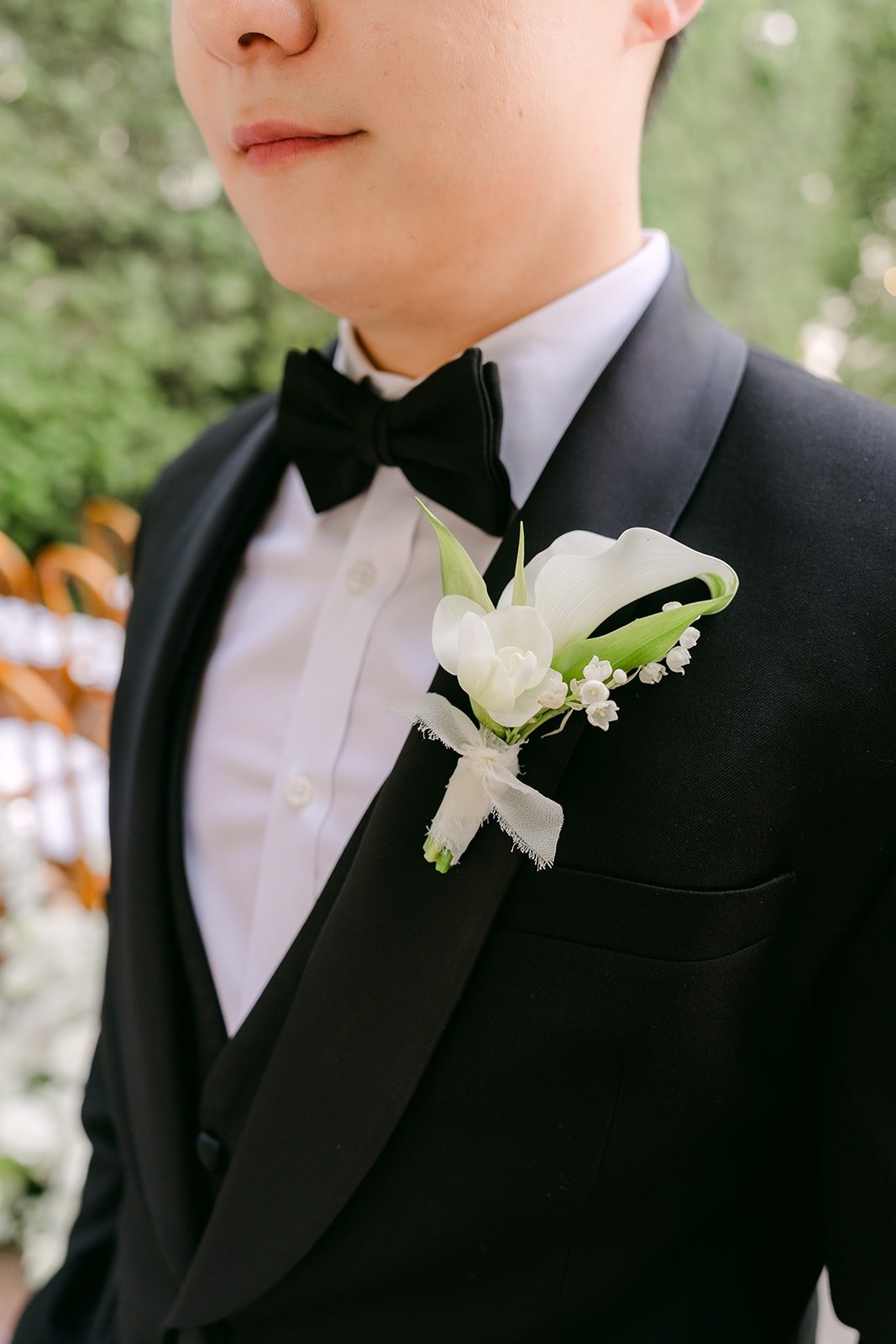 Min Soo's white boutonniere pinned to his black tuxedo, photographed by One and Only Production