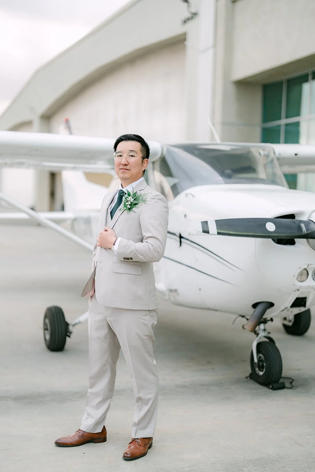 Groom portrait beside an airplane outside the hangar