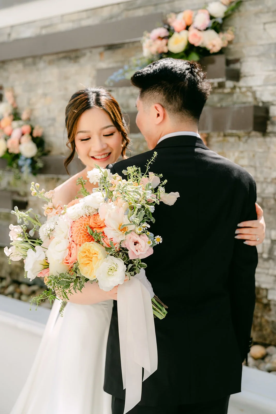 Amanda holding her bouquet as San wraps his arms around her.