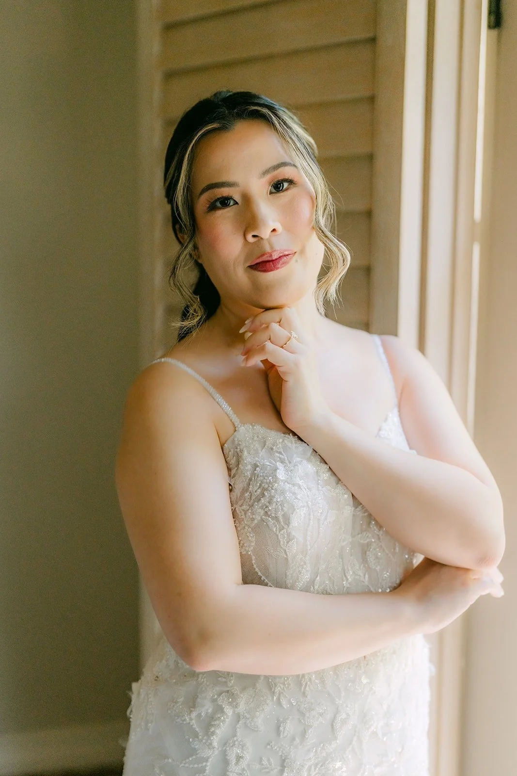 Joanne in her gown with her hand resting near her face in soft window light