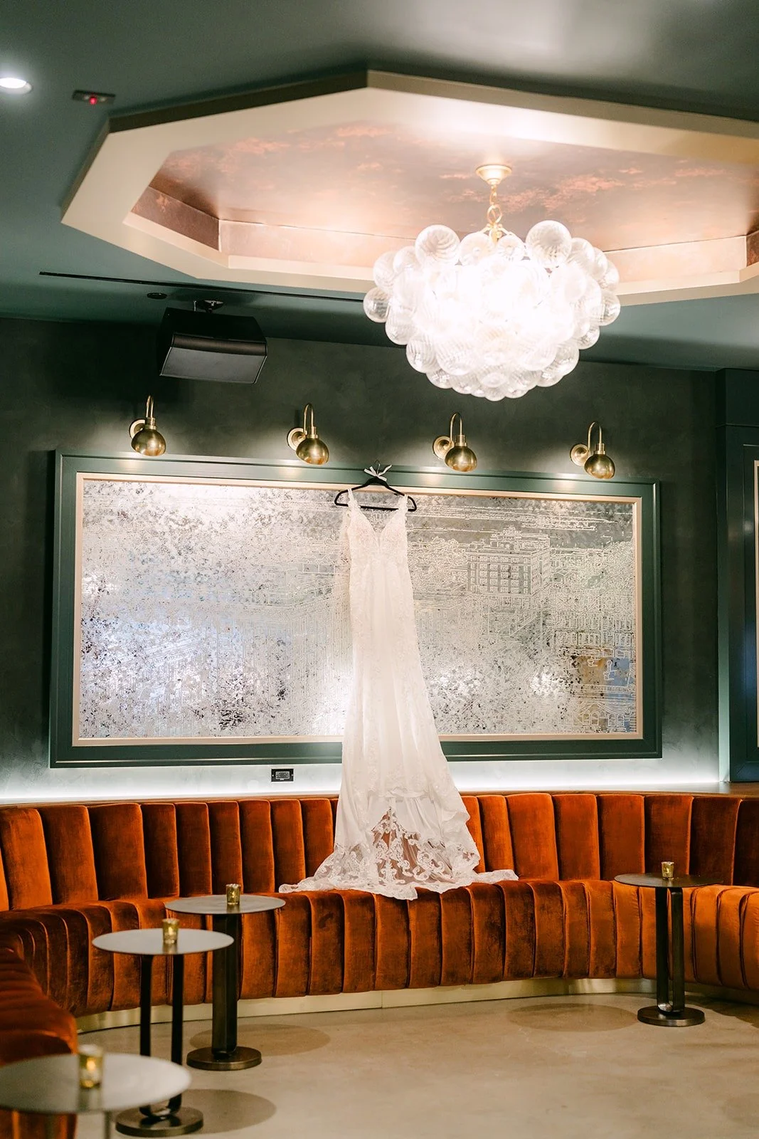 Elisa's wedding gown hanging under a chandelier in the bridal suite at The Headquarters