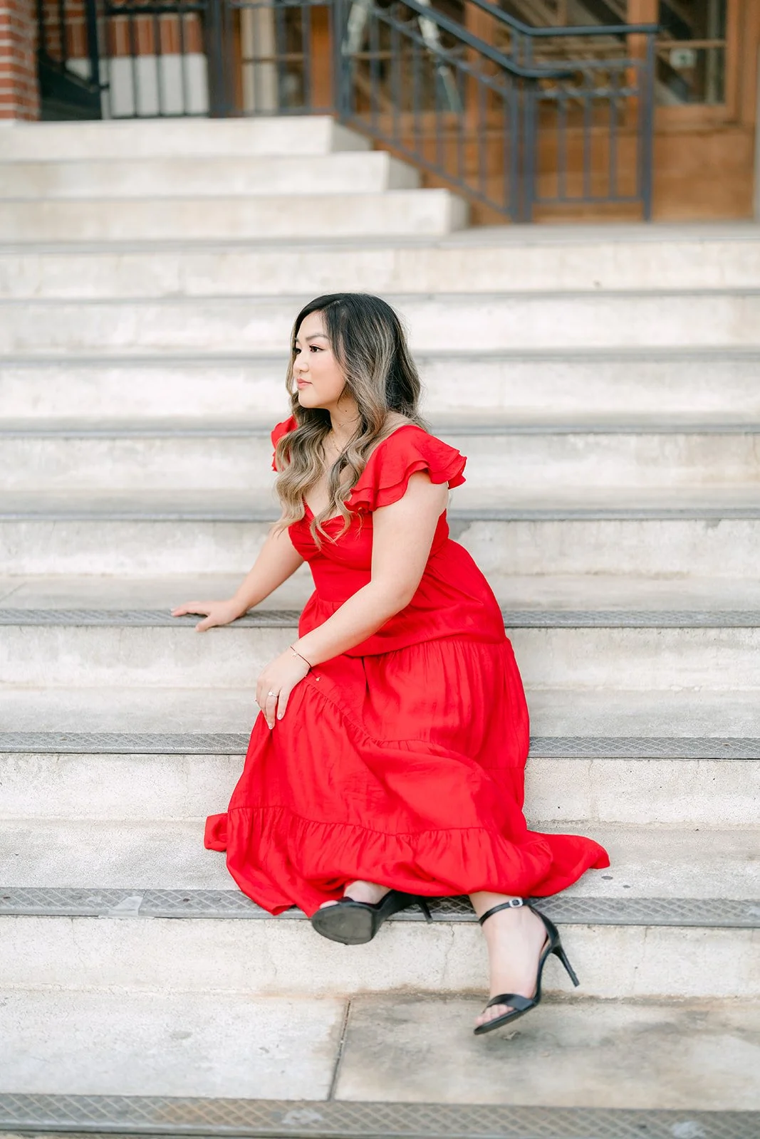 Linh seated on the stone steps in her red dress.