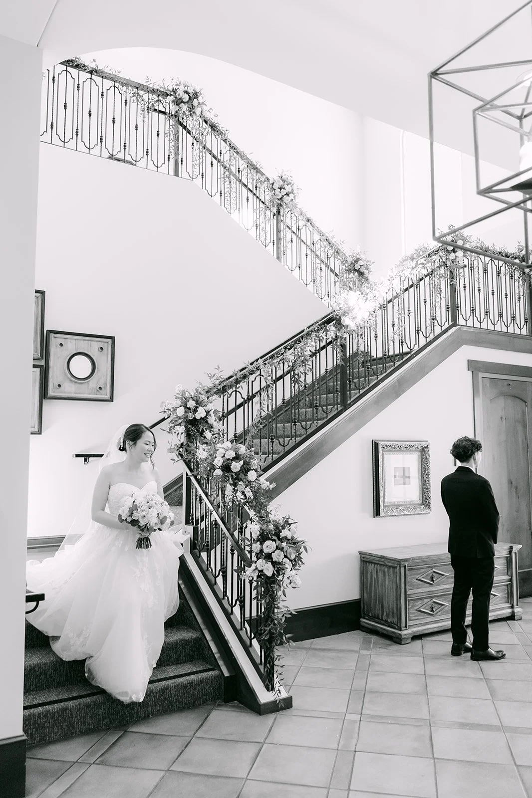 Black and white first look as the bride walks down the grand staircase toward Tony