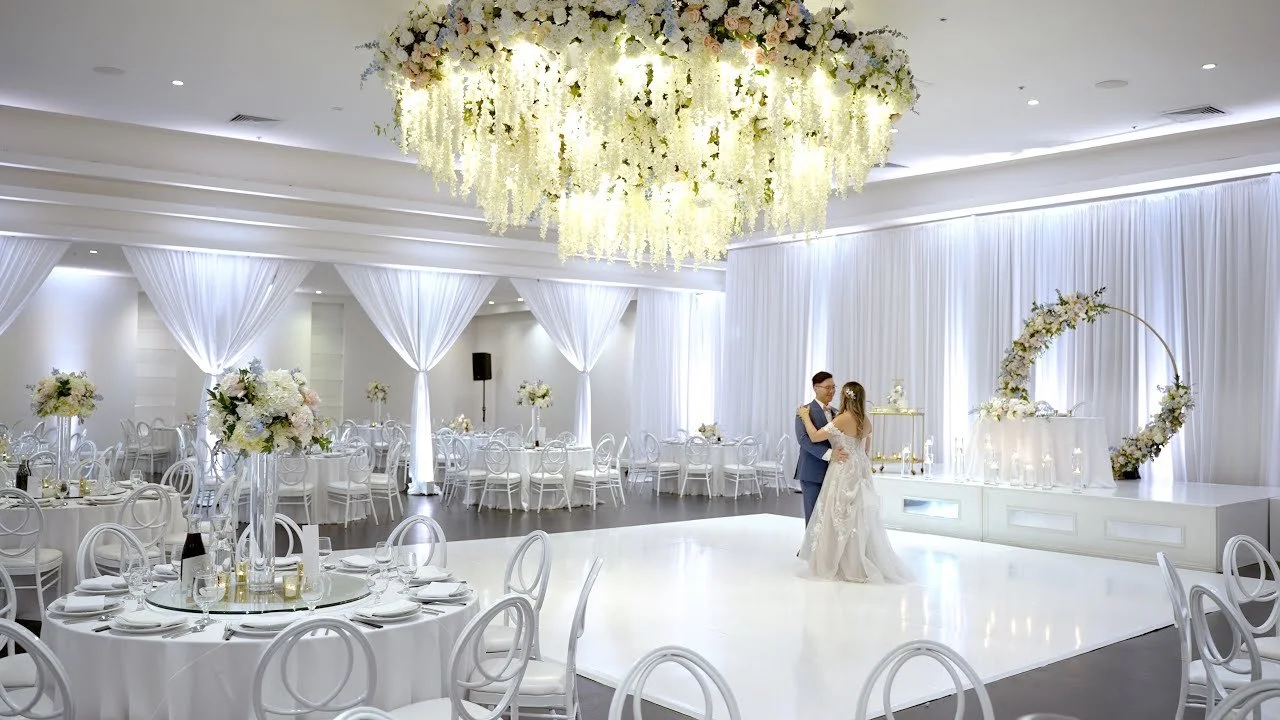 Video still of the white draped ballroom and crystal chandeliers at Venue by Three Petals, filmed by One and Only Production