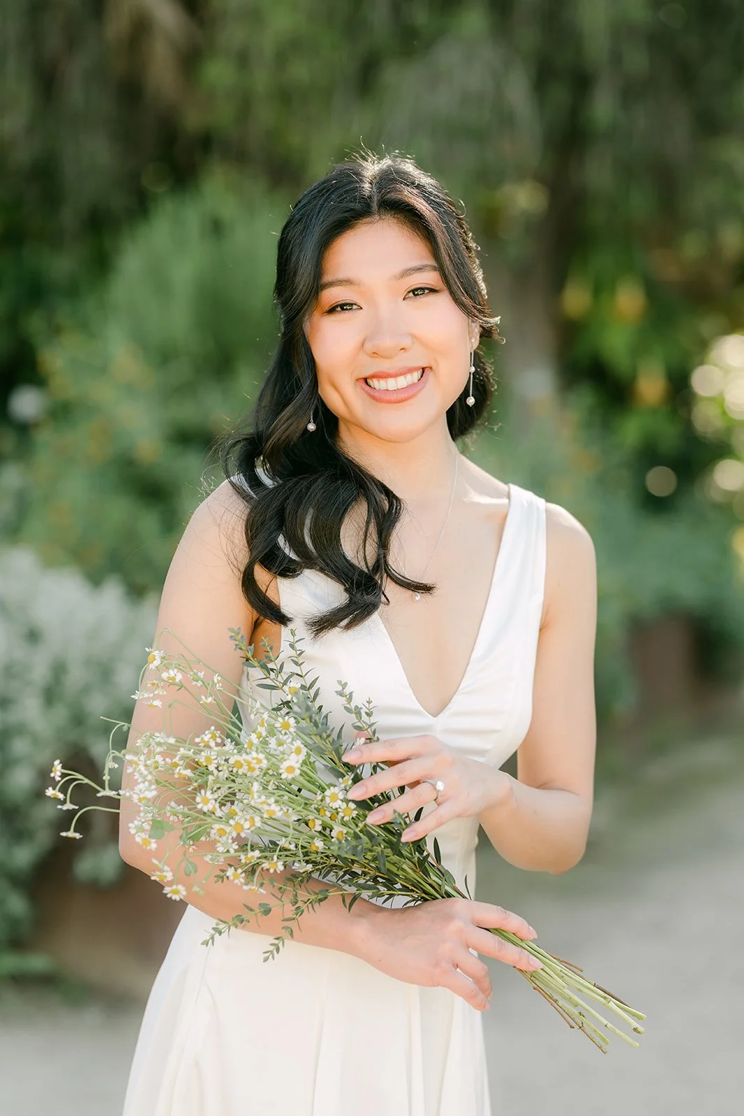 Kim smiling with her wildflower bouquet among the garden greenery.