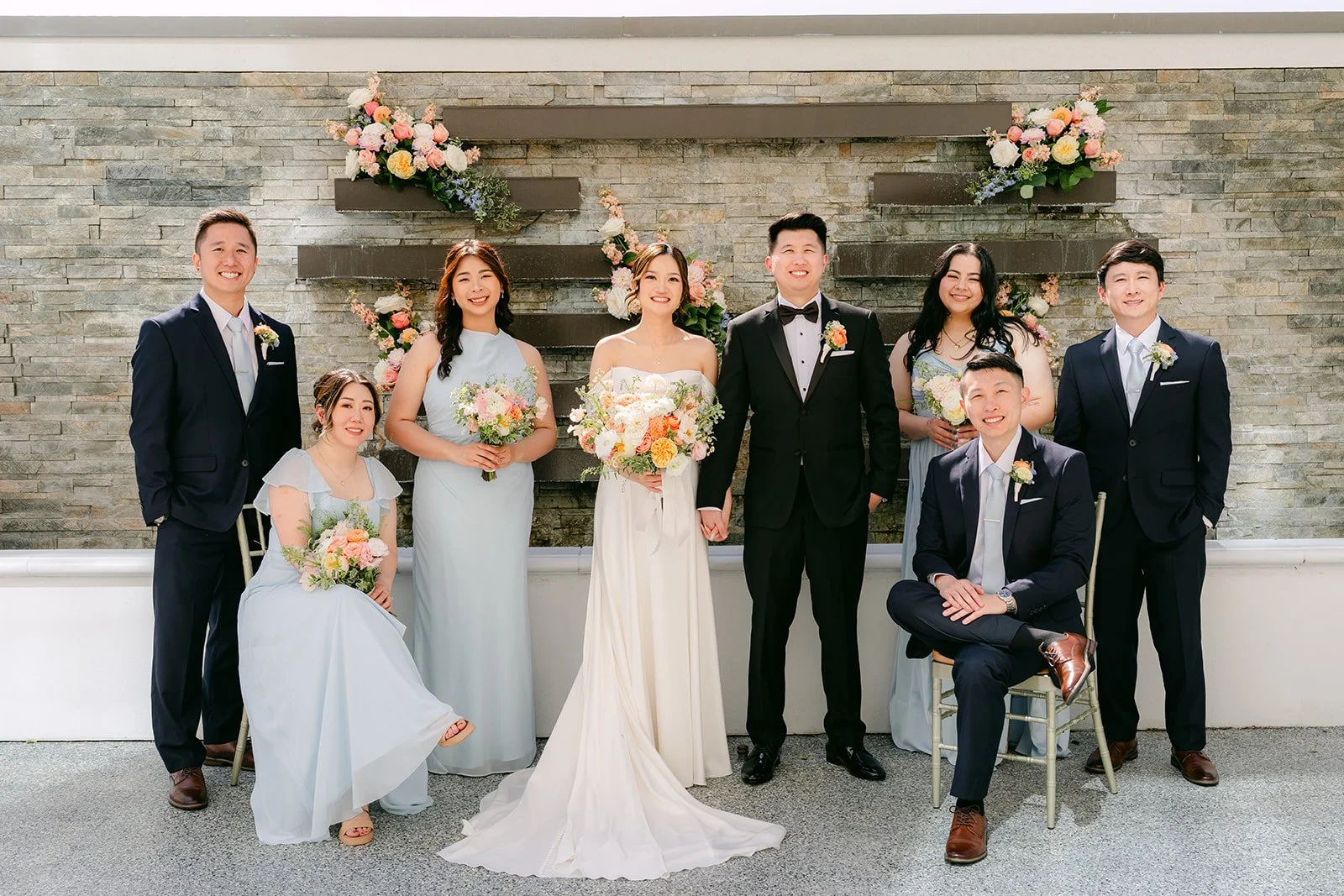 The full wedding party in black tuxedos and light blue dresses on the terrace.