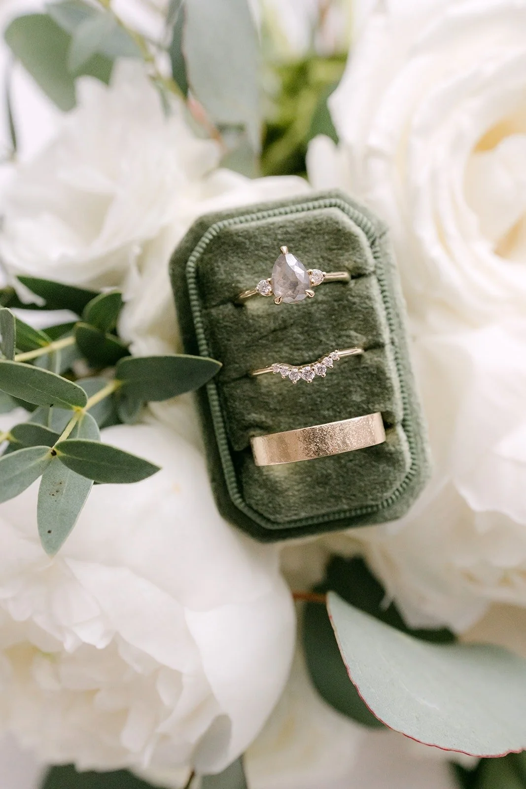 Wedding rings in a green velvet ring box among white roses