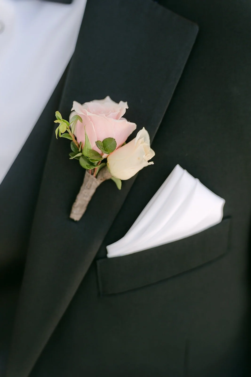 Kevin's pink rose boutonniere and white pocket square on his tuxedo lapel