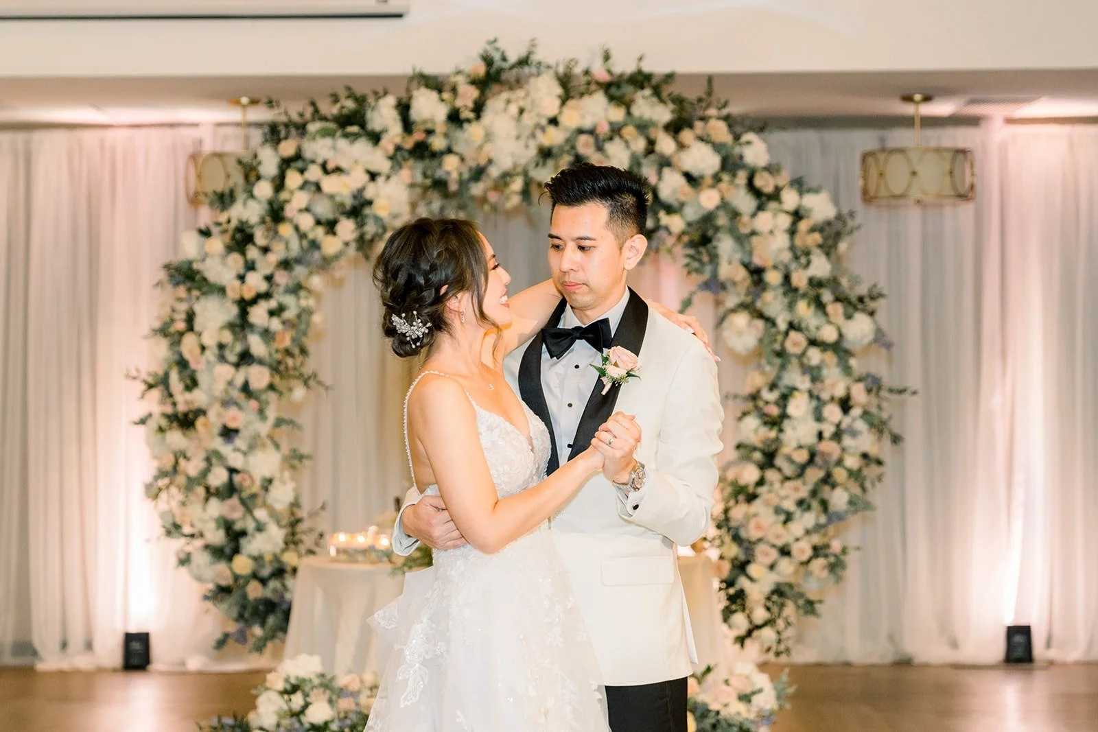 Josephine and David dancing in front of the floral arch