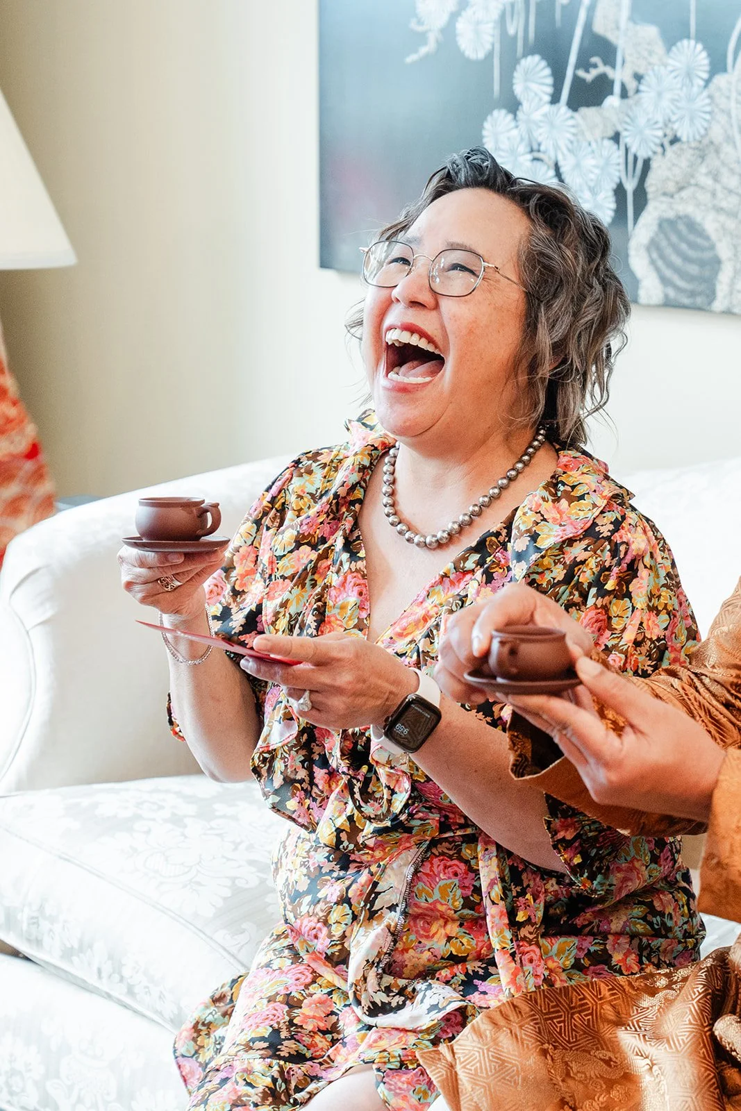 An elder laughing on the sofa during the tea ceremony.