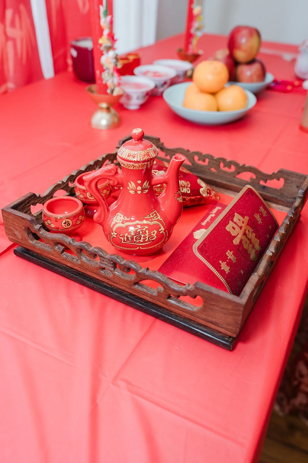 The tea set and fruit on the red table.