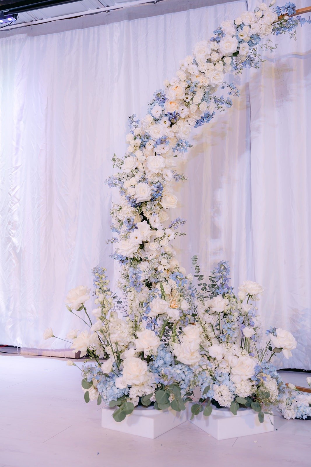 Crescent floral arch with white and blue blooms at Paracel Events