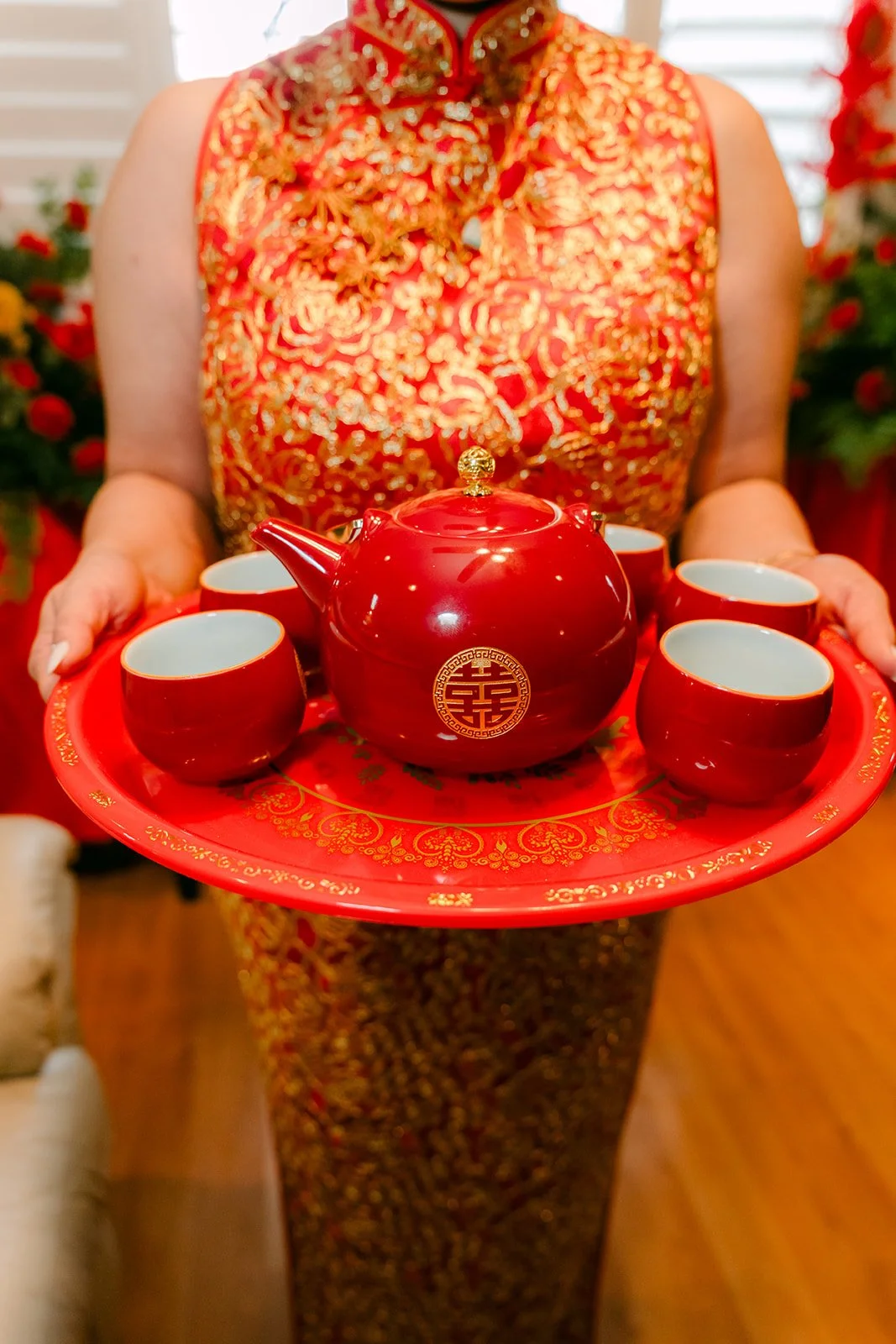 A bridesmaid in a red qipao holding the tea tray.