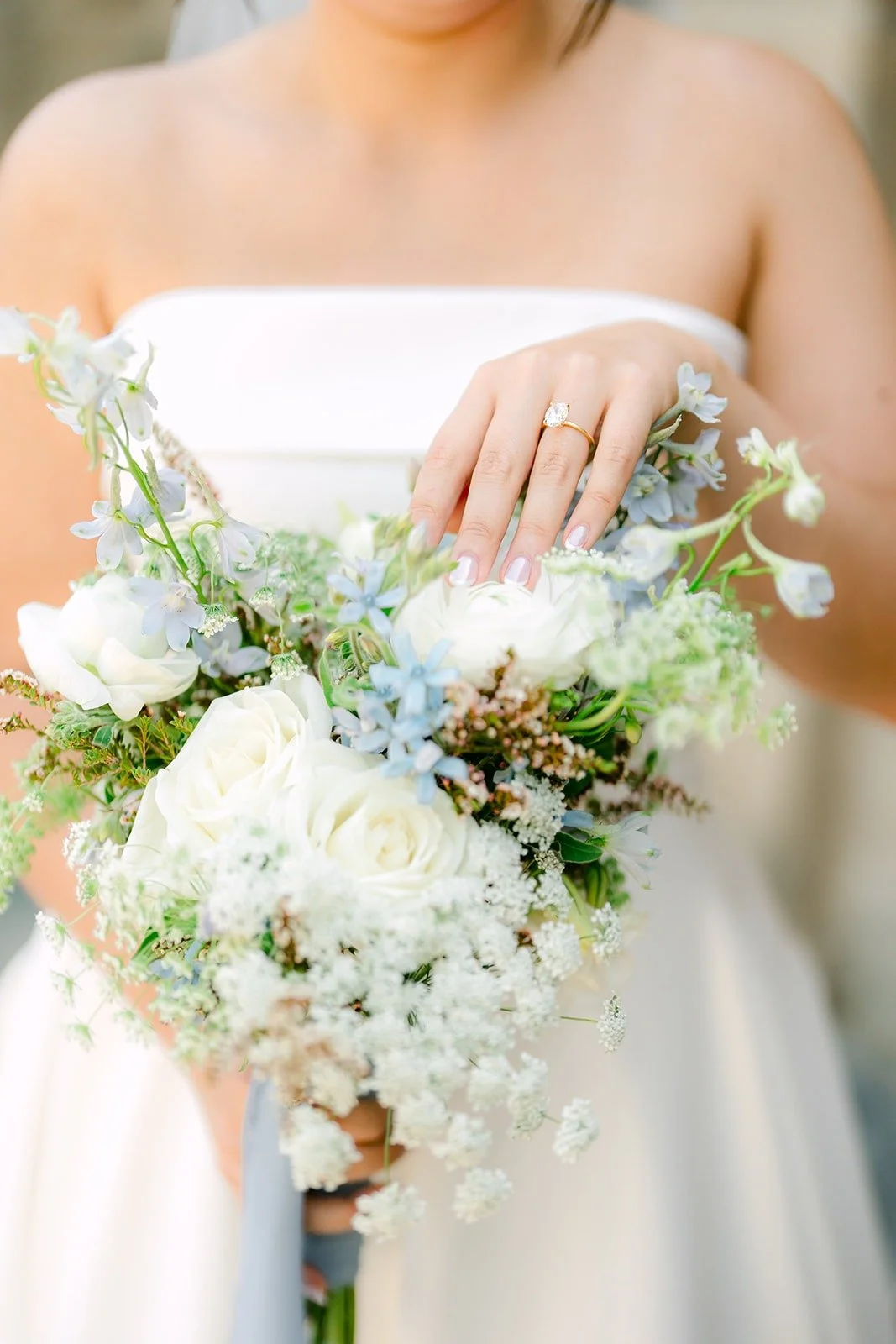Close up of Brianna's white and dusty blue bouquet and ring