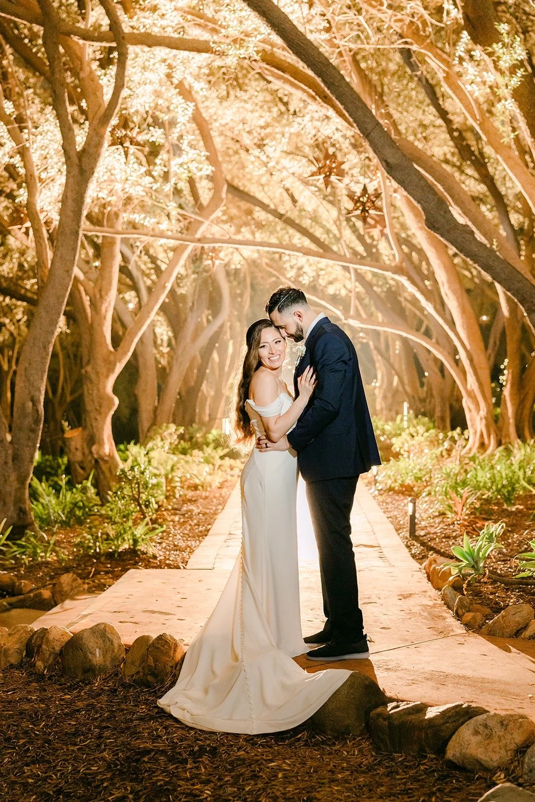 Mariana and Danny embracing on the path under the trees at night