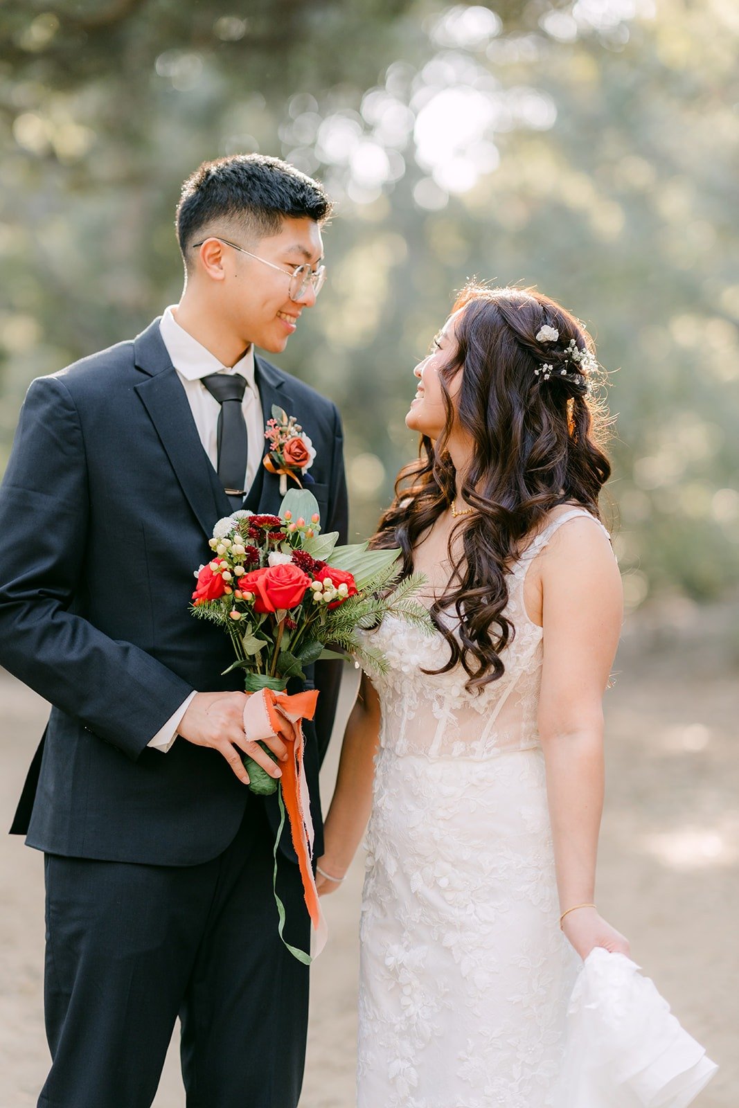 Shayna and Robert laughing together with her red rose bouquet between them