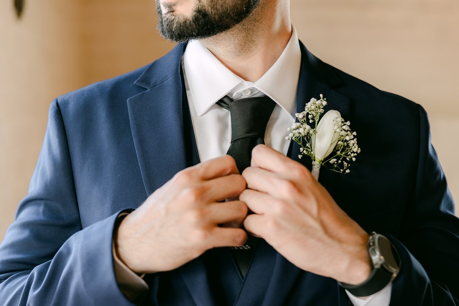 Danny buttoning his navy jacket, with his white boutonniere in view