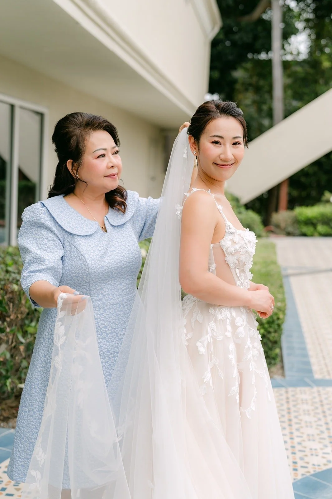 A family member helping Kylie with her veil outside the resort