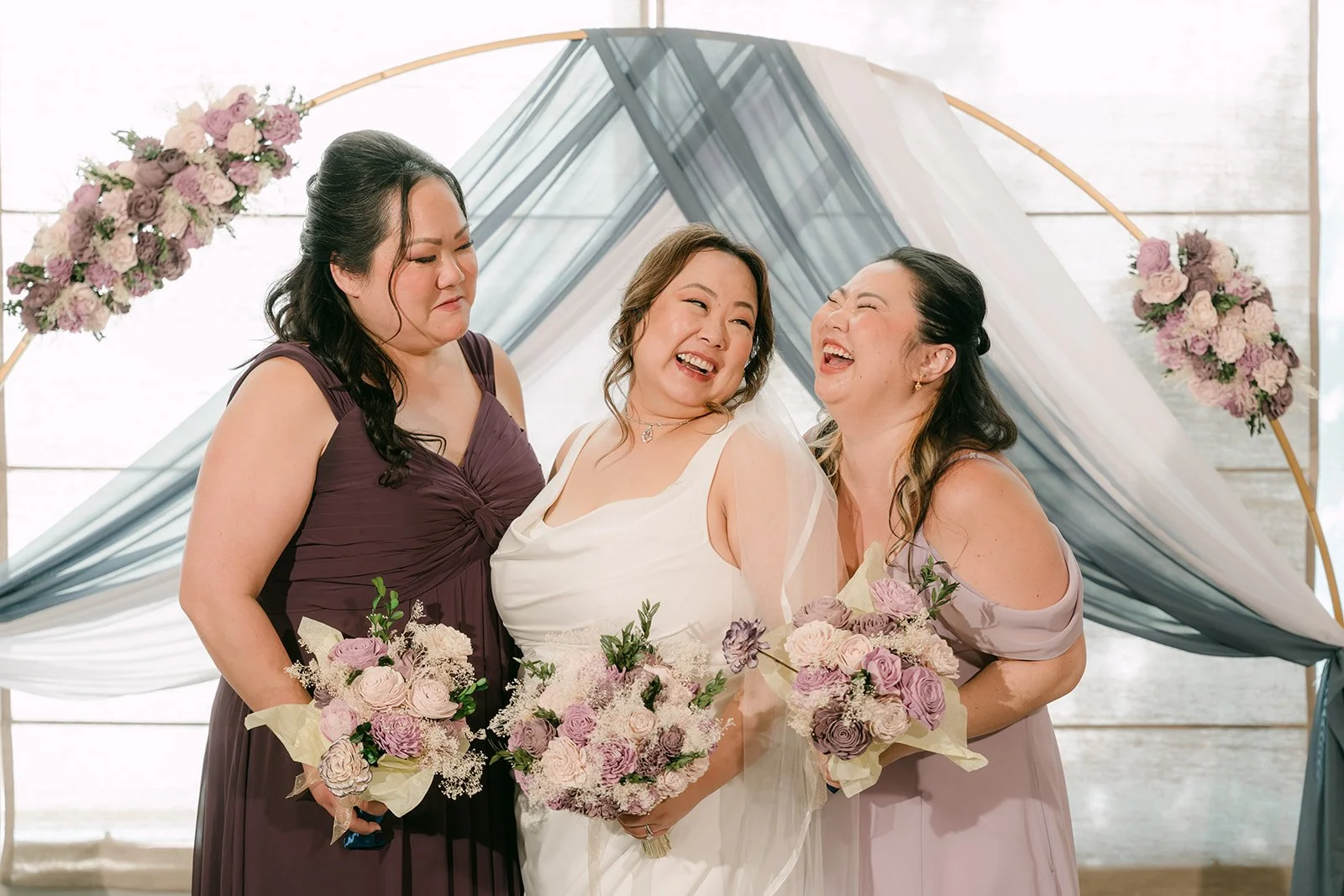 Mai and her bridesmaids in plum and lavender with their bouquets.