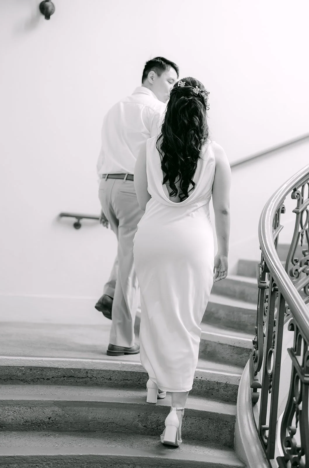 Black and white photo of James leading Emily up the curving staircase.