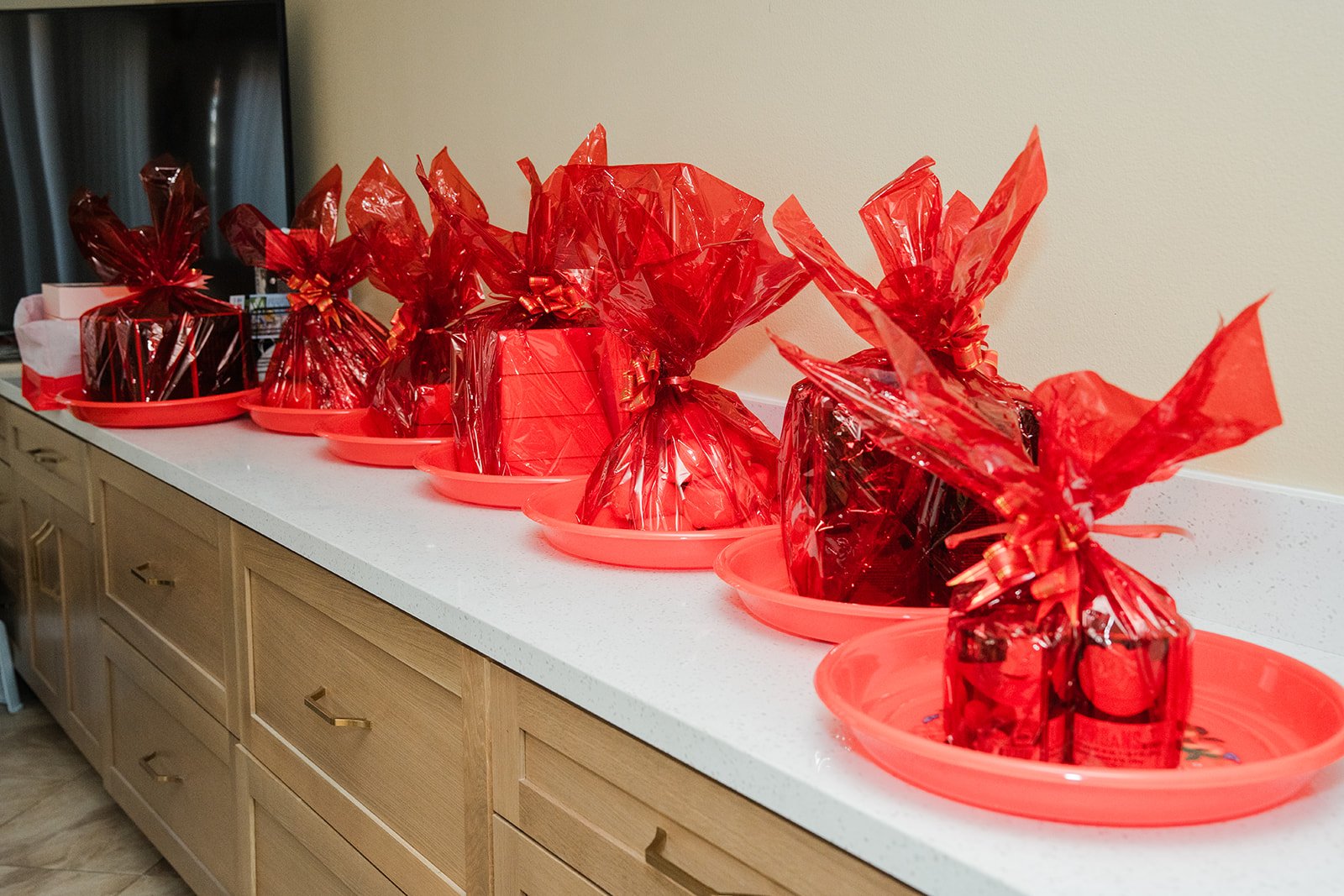Red wrapped gifts from the groom's family lined up on the counter, photographed by One and Only Production.