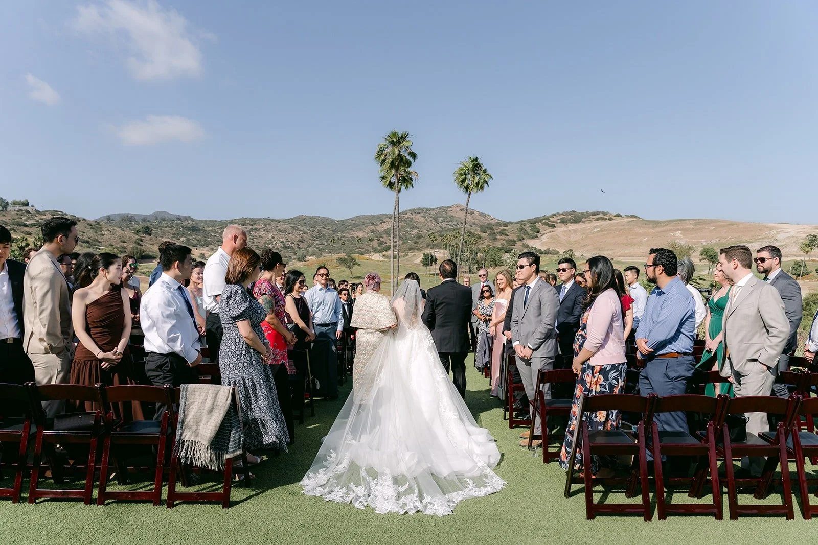 Joanne walking down the aisle as guests stand on the lawn
