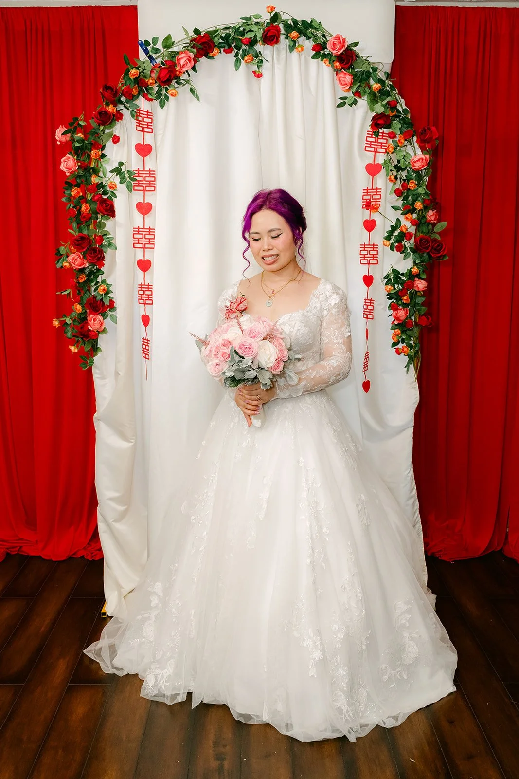 Vanessa holding her pink bouquet under the arch.