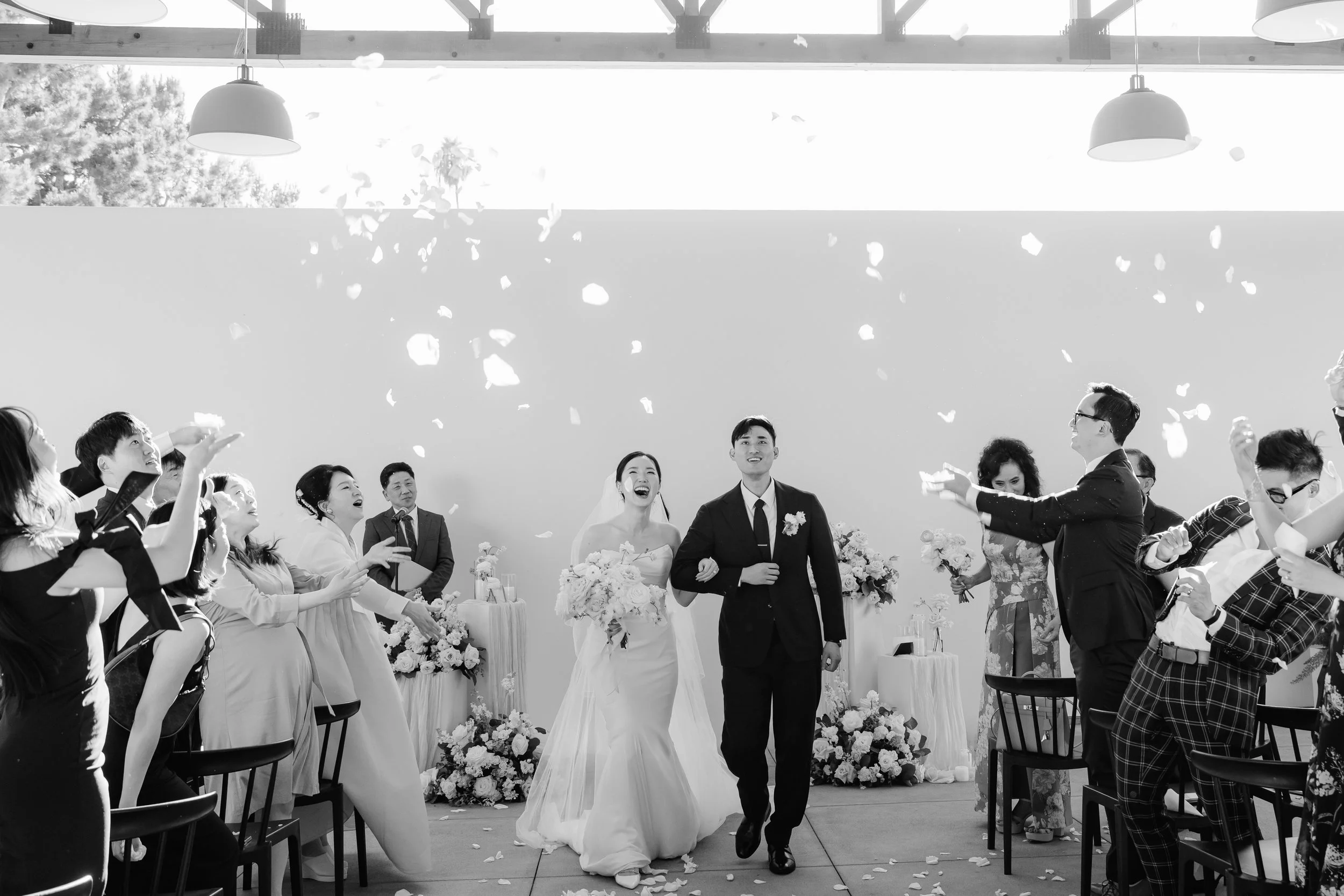 Bride and groom walk back up the aisle through a flower petal toss at their Southern California wedding