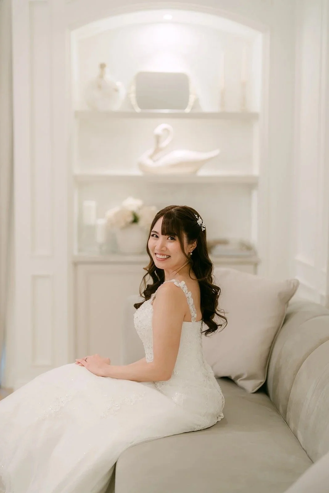Marina seated on a cream sofa in the bridal suite, glancing over her shoulder