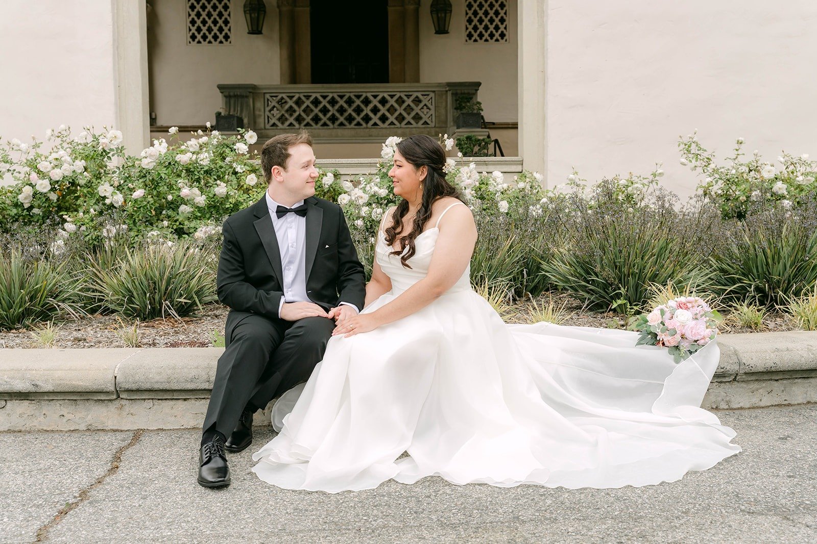 Saira and Matthew sitting together with her gown spread across the entrance walkway