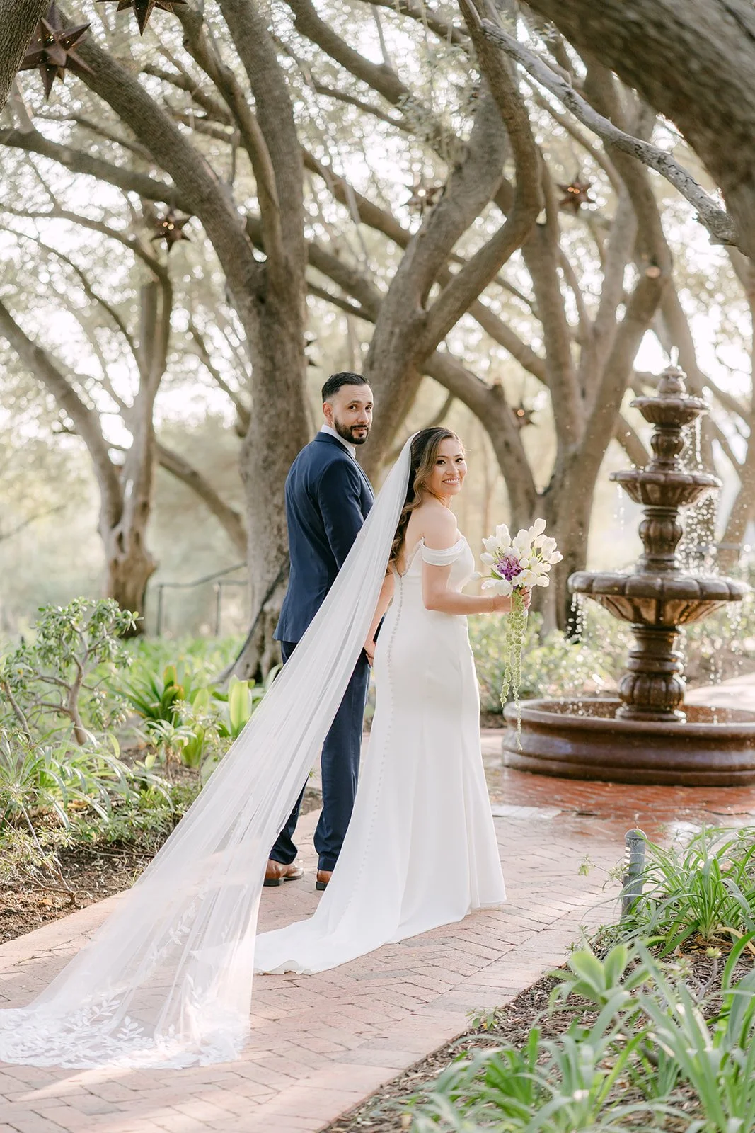 Couple beside the stone fountain at the edge of the olive grove