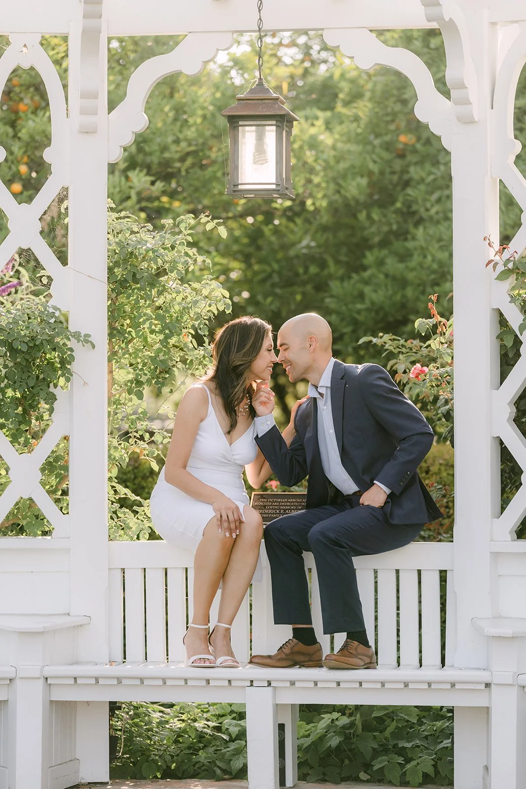Francesca and Daniel lean in close beneath the gazebo's hanging lantern.