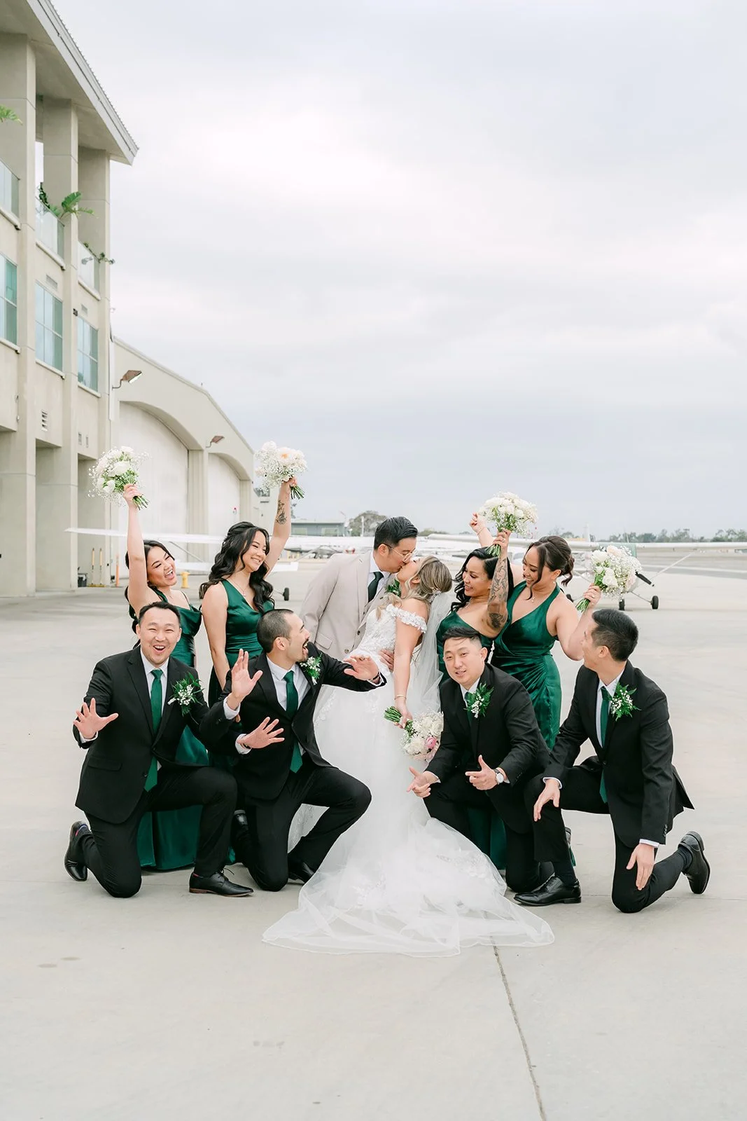 Wedding party cheering around the couple on the airport tarmac