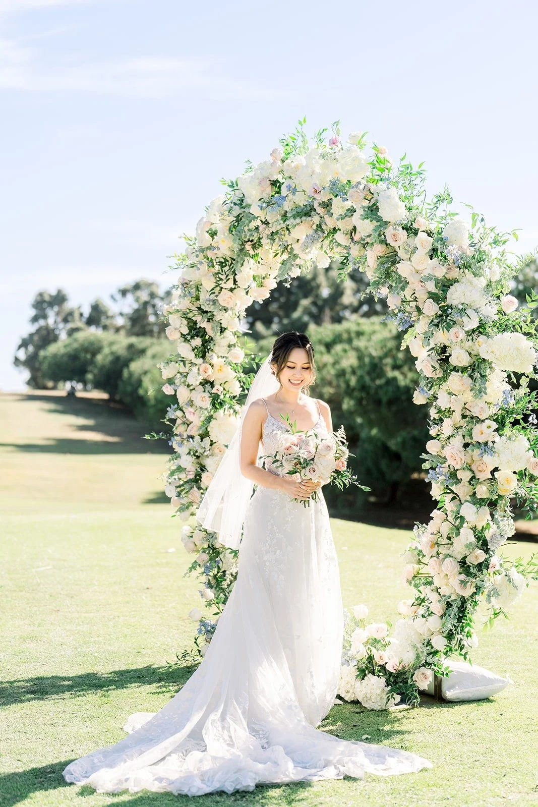 Josephine standing beneath the floral ceremony arch