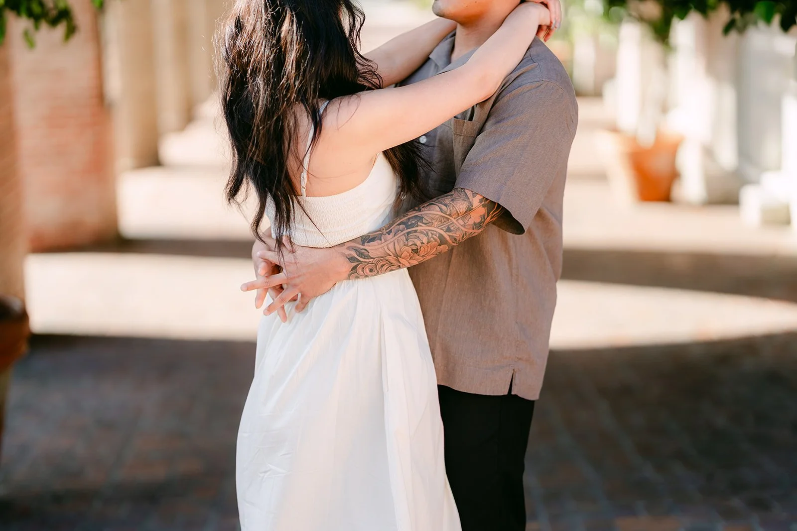 Victoria and Andrew hold each other in the shade of the plaza's arches.