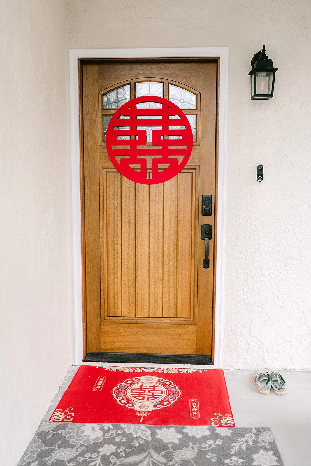 A red double happiness sign and red welcome mat on a family's front door on the morning of the tea ceremony.
