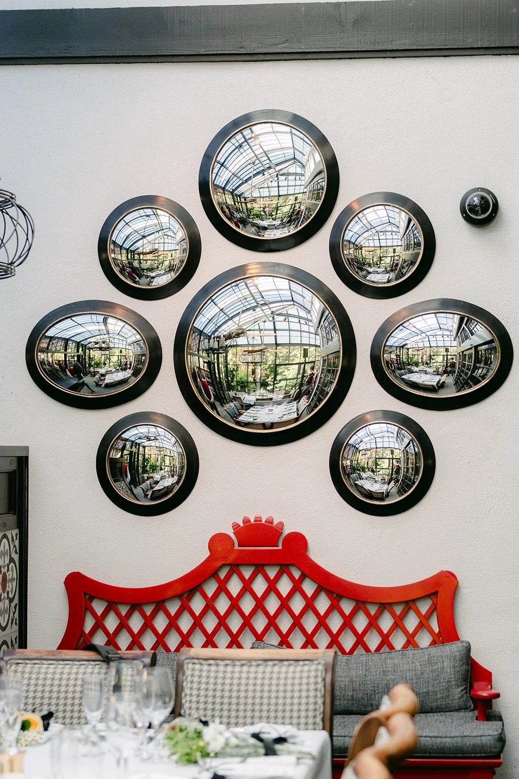 Round mirrors above a red carved bench in the dining room
