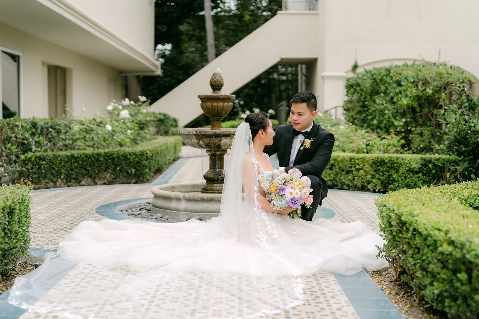 Kylie and Mario sitting by the fountain in the garden courtyard at Surf & Sand Resort