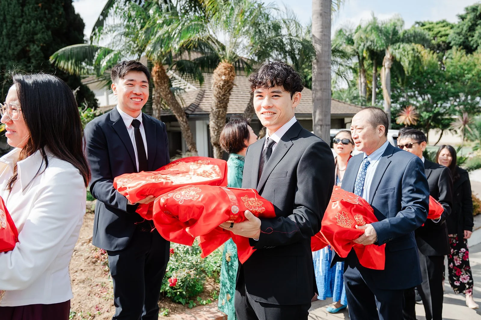 Henrik's family and groomsmen arriving with red covered gift trays.