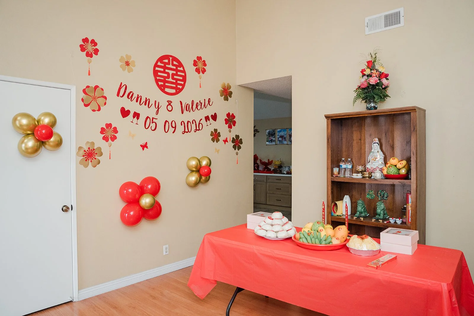 A Danny and Valerie backdrop with red and gold balloons.