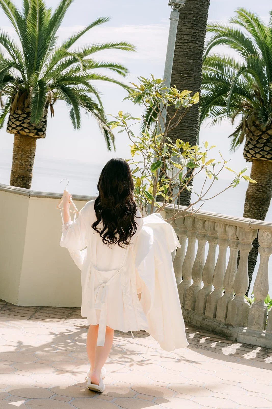 Bride walking along the terrace balustrade toward the ocean