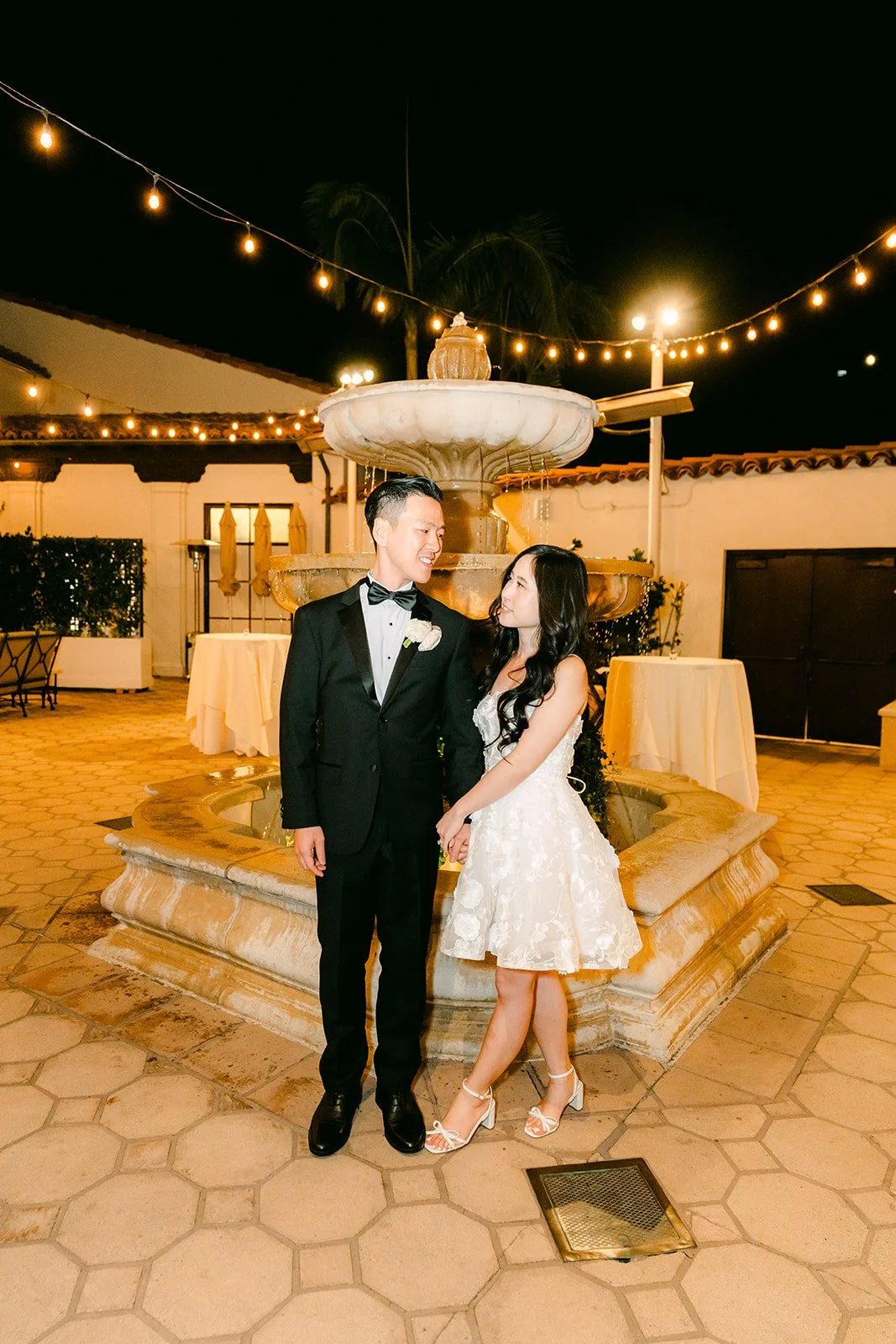 Couple by the courtyard fountain under string lights at night